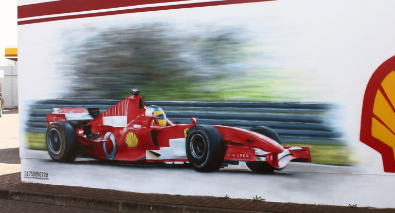 Graffiti auf einer Außenwand mit dem Motiv roter Formel 1 Ferrari und einem verschwommenen Hintergrund
